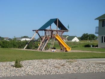 a playground with a swing set and a slide  at Meadows Edge Apartments - Detroit Lakes, Detroit Lakes